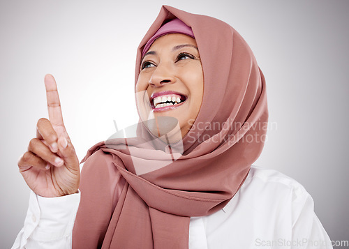 Image of Muslim, thinking and a woman with an idea in studio for happiness, kindness and positive attitude. Hijab, islam and islamic fashion with a mature person on grey background pointing up at announcement