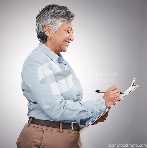 Image of Clipboard, writing and senior woman in a studio planning, brainstorming or working on a schedule. Happy, smile and elderly female model with a paper list and pen isolated by a gray background.