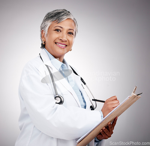 Image of Happy woman, portrait and doctor with clipboard in studio, planning notes or healthcare information. Mature medical worker writing report of insurance checklist, medicine or script on gray background