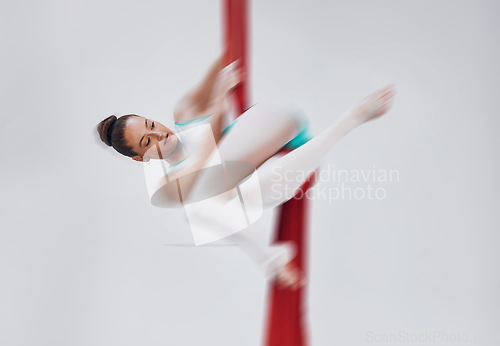 Image of Gymnastics, woman and aerial silk with a acrobat in air for performance, sports and balance. Young athlete person or gymnast hanging on red fabric and white background with space, art and creativity