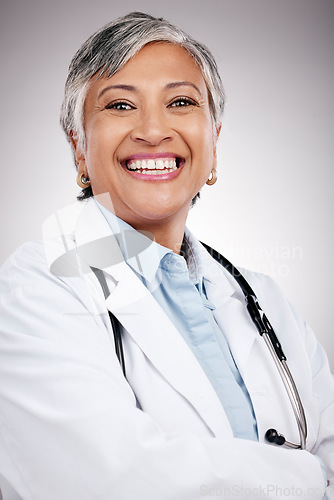 Image of Woman, portrait and doctor with arms crossed in studio for healthcare services, smile and consulting. Happy mature surgeon, expert therapist and medical professional with trust on gray background