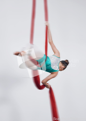 Image of Aerial silk, acrobat and a woman in air for gymnastics performance, sports and balance. Behind athlete person or gymnast hanging on red fabric and white background with space, art and creativity