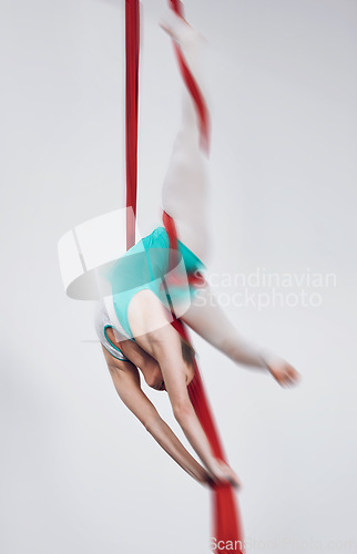 Image of Sport, acrobat and aerial silk with a woman in air for performance, gymnastics and balance. Young athlete person or gymnast hanging on red fabric and white background with space, art and creativity