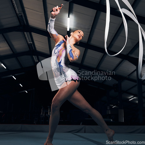 Image of Woman, ribbon and gymnastics in dance competition, performance or concert in dark arena. Dancer, rhythm training and athlete with talent, energy and creative movement for agile contest, skill or show