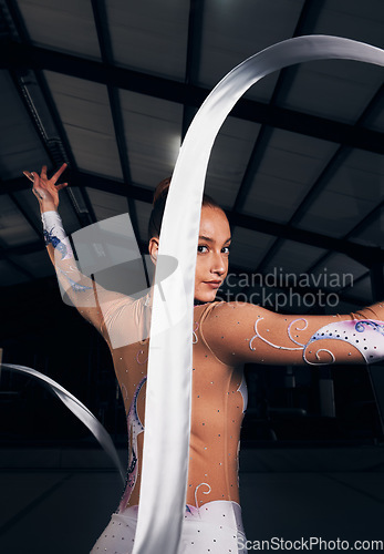 Image of Woman, portrait and ribbon gymnastics in dance competition, performance and concert in dark arena. Elegant dancer, rhythm and athlete training with talent for creative movement, contest and skill