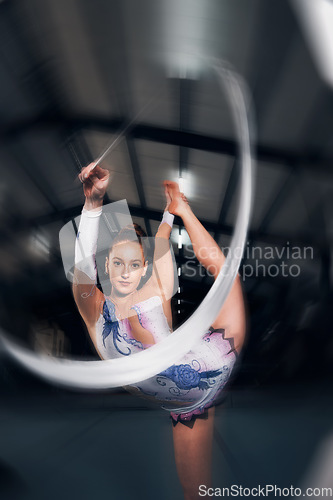 Image of Woman, portrait and motion for ribbon gymnastics in competition, performance or concert in dark arena. Flexible dancer, athlete and balance of action, agile training and talent in solo rhythm contest