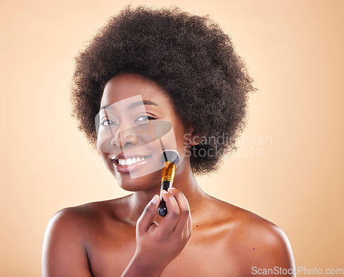 Image of Portrait, beauty and a black woman with a makeup brush for blush to apply cosmetics to her face. Smile, aesthetic and afro with a happy young model using a product on her skin to enhance appearance