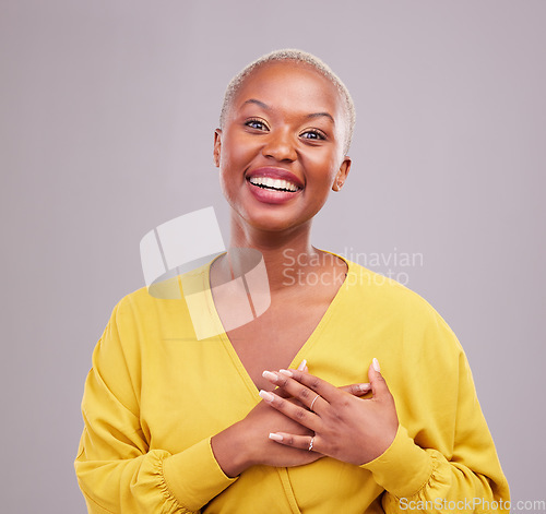 Image of Grateful, smile and portrait of a black woman in a studio with sweet, happy and positive attitude. Empathy, gratitude and young African female model with thank you gesture isolated by gray background