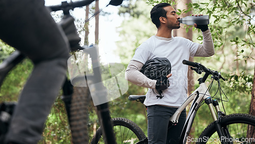 Image of Forest, bike and man drinking water, exercise and fitness with workout, refreshing and wellness. Healthy person, athlete or cyclists in the woods, hydration and outdoor with liquid, nature and helmet