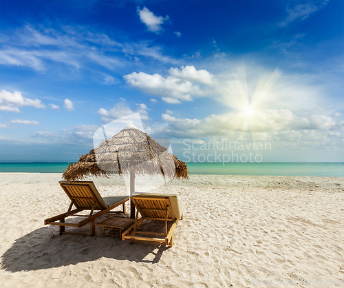 Image of Two beach lounge chairs under tent