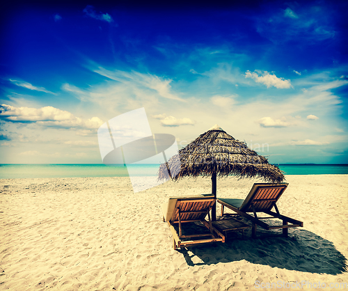 Image of Two lounge chairs under tent on beach