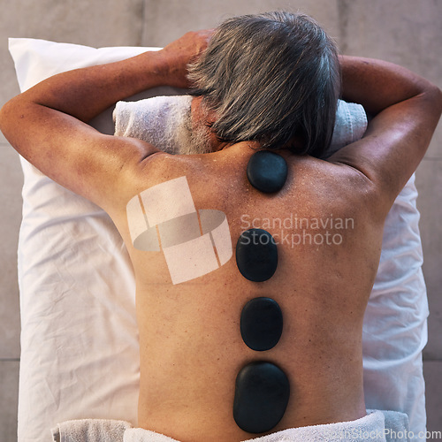 Image of Hot stone massage and back of man in spa for wellness, holistic treatment and hospitality. Peace, cosmetics and beauty salon with body of customer at hotel for relax, vacation and physical therapy