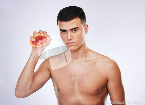 Image of Skincare, grapefruit and squeeze with portrait of man in studio for beauty, detox and natural cosmetics. Vitamin c, nutrition and spa with person and fruit on white background for self care and glow