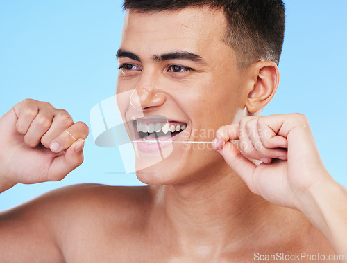 Image of Happy man, face and dental floss in teeth cleaning, hygiene or grooming against a blue studio background. Male person or model smile with flossing in oral, tooth whitening or gum and mouth care