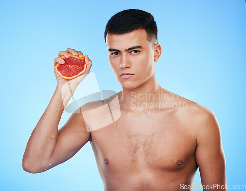 Image of Squeeze, grapefruit and skincare with portrait of man in studio for health, detox and natural cosmetics. Vitamin c, nutrition and spa with person and fruit on blue background for self care and glow