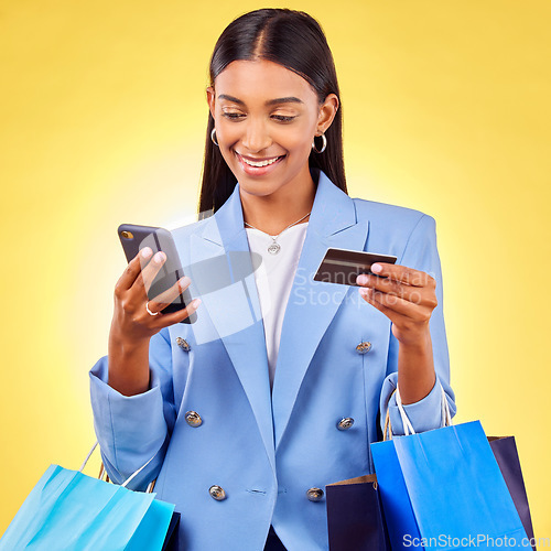 Image of Woman, phone and credit card with shopping bag, studio and fintech for payment by yellow background. E commerce, smartphone and banking info with smile, discount and sale on mobile app for fashion