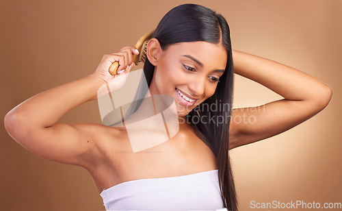 Image of Beauty, smile and woman brushing hair in studio for growth, texture or shine against a brown background space. Haircare, cosmetics and female wellness model with brush, tool or hairstyle satisfaction