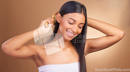 Image of Beauty, smile and Indian woman with hair brush in studio for shampoo, results or scalp wellness on brown background. Haircare, texture and lady model happy with growth, keratin or volume satisfaction