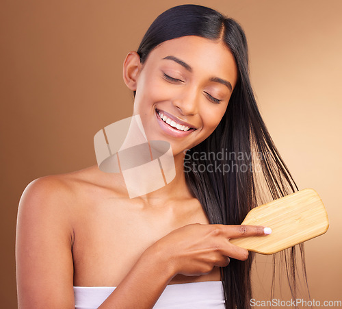 Image of Smile, hair care and woman with a brush, glow and natural beauty on a brown studio background. Person, girl or model with style, luxury or shampoo with texture, comb or cosmetics with shine or volume