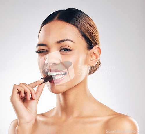 Image of Chocolate, wink and portrait of woman in studio with diet, detox or sweet, unhealthy and snack on white background. Face, emoji and female model with sugar, candy bar or eating isolated cocoa treats