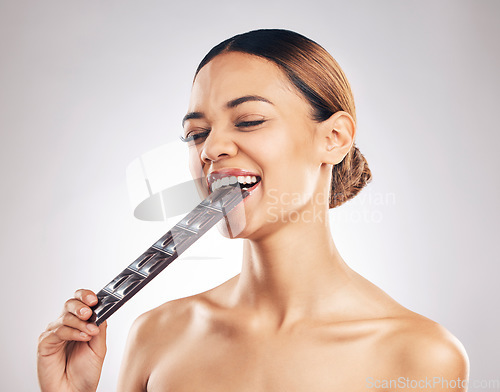 Image of Skincare, diet and happy woman in studio with dark chocolate for anti aging benefits on white background. Sugar, beauty and lady model face, smile and eat candy bar for collagen, diet or pigmentation