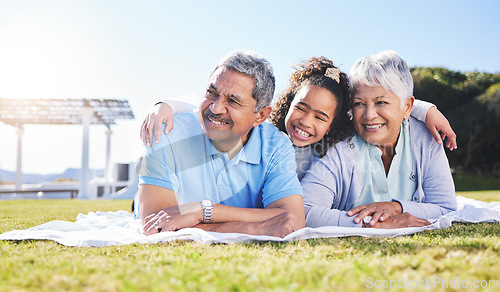 Image of Grandparents, girl and blanket on grass, relax and smile with hug, love and picnic on family vacation in summer. Senior man, woman and grandchild with embrace, thinking and happy in sunshine on lawn