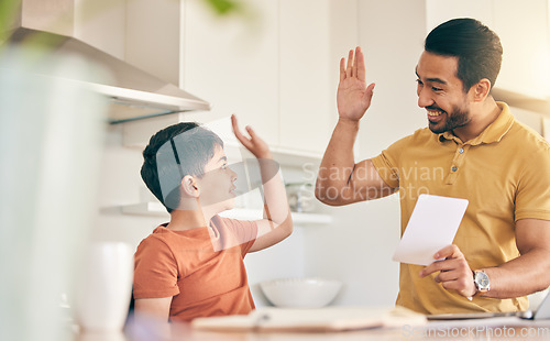 Image of High five, homework and father with child at their home in celebration of completed studying. Happy, smile and young dad bonding together with his boy kid in the kitchen of modern house or apartment.