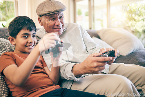 Image of Family, fun and a boy gaming with his grandfather on a sofa in the living room of their home during a visit. Video game, children and a senior man learning how to play from his gamer grandson