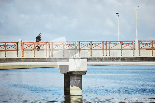 Image of Exercise, sky and a man running on a bridge for a cardio or endurance workout on cloud mockup space. Fitness, sports and training for a marathon with a male runner or athlete outdoor for a challenge