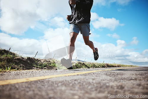 Image of Legs, fitness and running with a man on a road on a blue sky and clouds for cardio training in a race. Exercise, health and challenge with a male runner or athlete outdoor for a workout or marathon