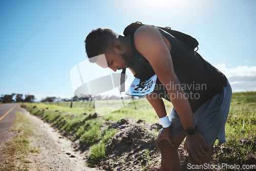 Image of Fitness, breathing and tired man in road for training, workout or intense cardio outdoor performance. Sports, fatigue and male runner stop break, recover or dehydration during resilience competition