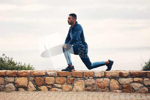 Image of Man, lunge and stretching on rocks, outdoor earphones or for thinking, music for fitness, health or wellness. Runner guy, warm up and training for marathon with streaming, vision or workout in nature