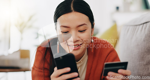 Image of Asian woman, credit card and phone relaxing on her sofa online shopping, ecommerce and fintech easy payment. Young person in China typing bank information on cellphone for finance transaction at home