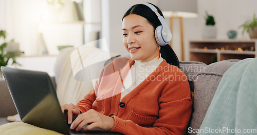 Image of Laptop, headphones and asian woman on couch with work from home opportunity in online or website copywriting. Remote worker or person in china typing on her computer and listening to music at home