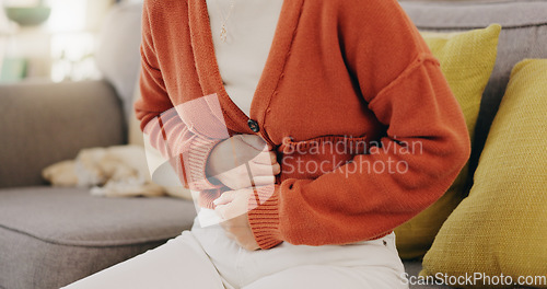 Image of Stomach ache, cramps and hands of woman with abdomen pain due to constipation, menstruation or ibs issue. Sick, home and person suffering and holding belly in a house lounge, couch and living room