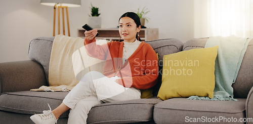 Image of Watching tv, relax and an Asian woman on a sofa in the living room of her home streaming a subscription service. Television, channel surfing and comedy with an attractive young female sitting in her