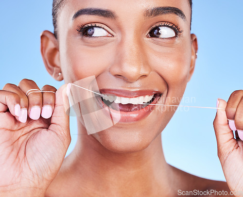 Image of Woman, smile and floss teeth in studio for healthy dental care, gum gingivitis or plaque on blue background. Face, happy indian model and oral thread for cleaning mouth, fresh breath or tooth hygiene