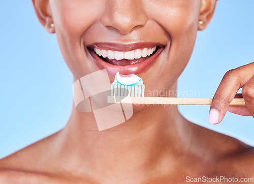 Image of Closeup, mouth or woman brushing teeth in studio for dental care, fresh breath or healthy smile on blue background. Face of happy model, eco friendly bamboo toothbrush and toothpaste of oral cleaning