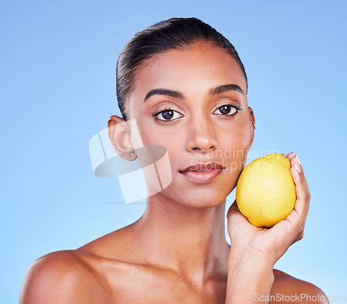 Image of Lemon, portrait or natural skincare of woman in studio for vitamin c benefits, eco cosmetics or nutrition. Face of indian model, healthy beauty or citrus fruit of vegan dermatology on blue background