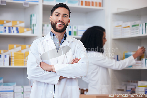 Image of Medicine, pharmacy and portrait of healthcare man at shelf with pills, stock or medication. Pharmacist person or medical staff with arms crossed and smile at pharmaceutical, drugstore or retail shop