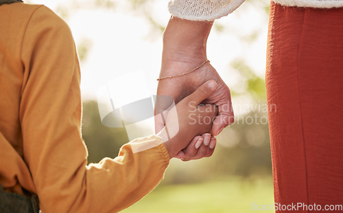 Image of Mother, kid and holding hands for walking in park for support, trust and care together or bonding in nature. Love, comfort and parent help child in the morning sunshine with kindness on weekend