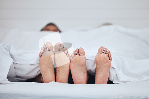 Image of Couple, bed and feet with blanket in sleeping, peace and morning rest together on weekend at home. Barefoot people, asleep and comfort in bonding, care or love under duvet in bedroom at the house