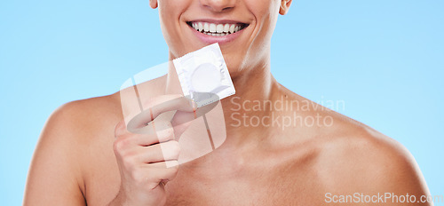 Image of Smile, hand and man with a condom on a blue background for security or birth control in sex. Happy, health and person or guy showing protection or a product for sexual safety choice or contraception