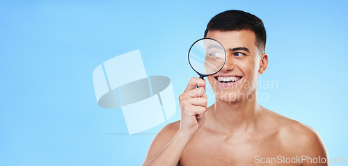 Image of Magnifying glass, skincare and man on blue background for wellness, healthy skin and mockup space. Dermatology, banner and face of person with lens for acne treatment, cosmetics and beauty in studio