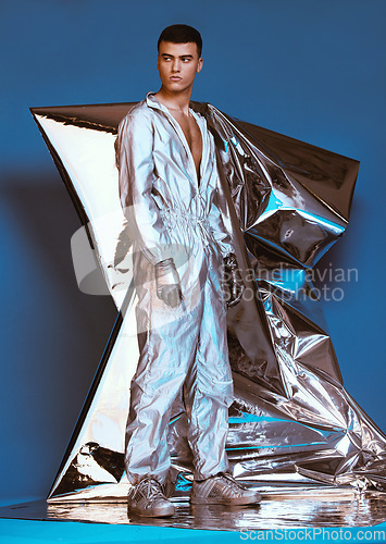 Image of Holographic, vaporwave fashion and man with futuristic ski style with sci fi clothing in studio. Art, creative and male model with trendy, cool and cyberpunk designer clothes with blue background