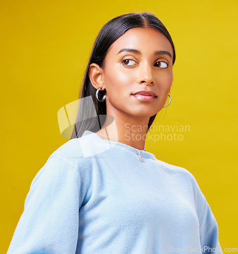 Image of Beauty, fashion and thinking with an indian woman on a yellow background in studio for trendy style. Mindset, idea and clothes with a young gen z model posing in clothes outfit for a magazine