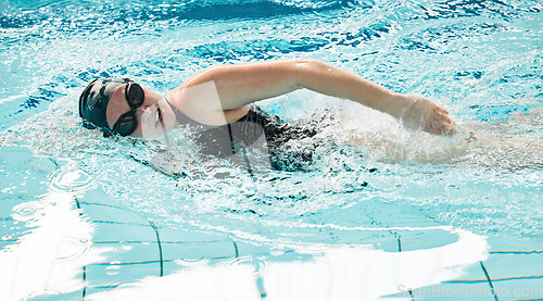 Image of Woman, pool and swimming in water for exercise, sports fitness or training in athletic triathlon. Female person, athlete or professional swimmer in competition, race or marathon in workout practice