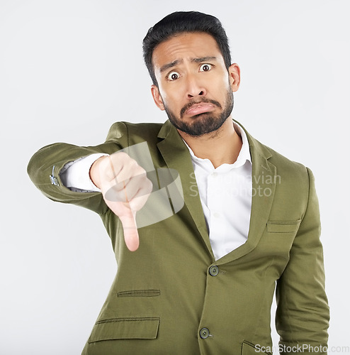 Image of Portrait, frown and man with thumbs down in studio for rejection, no or bad review on white background. Face, sad and Japanese model with emoji hand for negative, vote or feedback fail and opinion