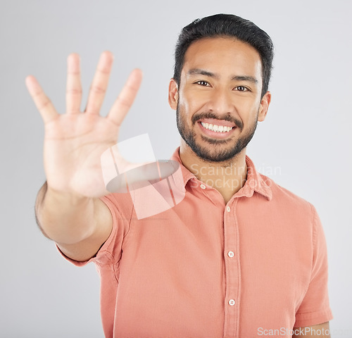 Image of Smile, hand and portrait of man with stop gesture happy for communication isolated in a studio white background. Asian, sign language and confident young person with signal, symbol and hello sign