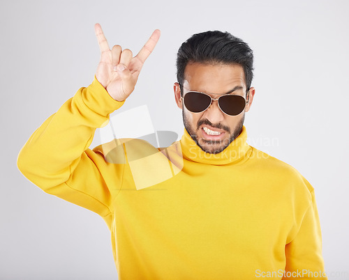 Image of Man, sunglasses and horns sign in studio portrait, rock icon or hand gesture with clothes by white background. Young guy, model and devil fingers for attitude, fashion or crazy with emoji for culture